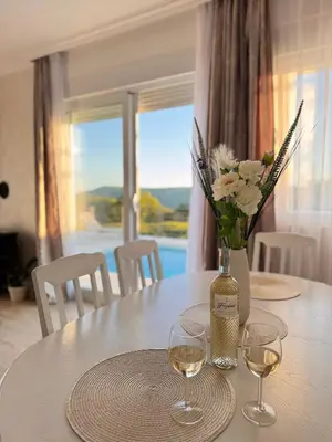 a table with a vase of flowers and wine glasses at Villa Aurora in Gorovići