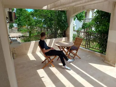 a man sitting in a chair on a patio at Jasmin 2 in Ulcinj
