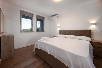 a bedroom with a large bed and two windows at Gjerana SEAVIEW in Ulcinj