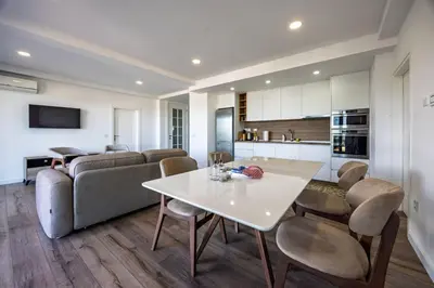 a kitchen and living room with a white table and chairs at Gjerana SEAVIEW in Ulcinj
