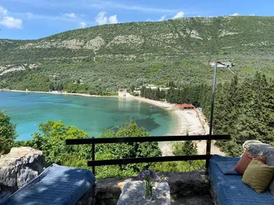 a view of a beach with a blue couch at Stone & Sea house in Valdanos