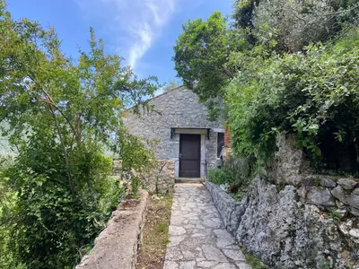 an old stone house with a door on a hill at Stone & Sea house in Valdanos