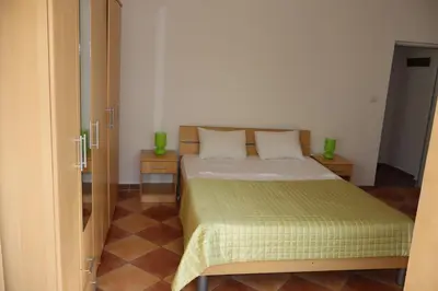a bedroom with a bed with a green bedspread at Apartmani Mulic in Sutomore