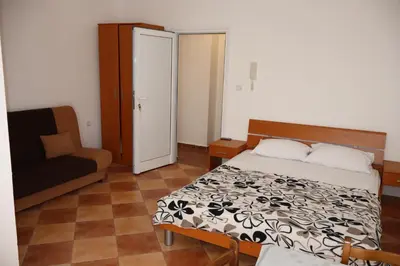 a small bedroom with a bed and a chair at Apartmani Mulic in Sutomore