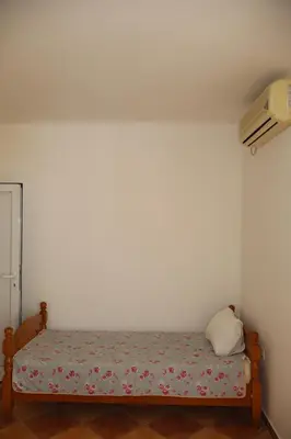 a small bed in a corner of a room at Apartmani Mulic in Sutomore