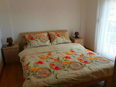 a bed with a floral comforter with two night stands at Cosy 1 bedroom apartment BUDVA in Budva
