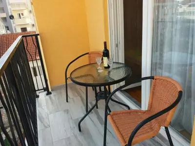 a table with a bottle of wine and two chairs on a balcony at Cosy 1 bedroom apartment BUDVA in Budva