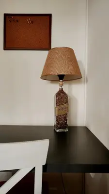 a bottle of whiskey sitting on a table with a lamp at Cozy & Bright Garden Flat in Podgorica