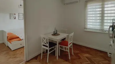 a small table and chairs in a room with a bed at Cozy & Bright Garden Flat in Podgorica