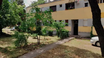 a yellow building with a car parked in front of it at Cozy & Bright Garden Flat in Podgorica