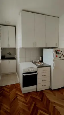 a kitchen with white cabinets and a stove and refrigerator at Cozy & Bright Garden Flat in Podgorica