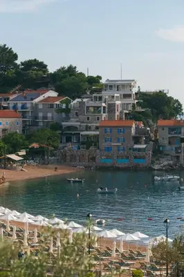 a beach with umbrellas and boats in the water at Summer vacation near Sveti Stefan in Podličak