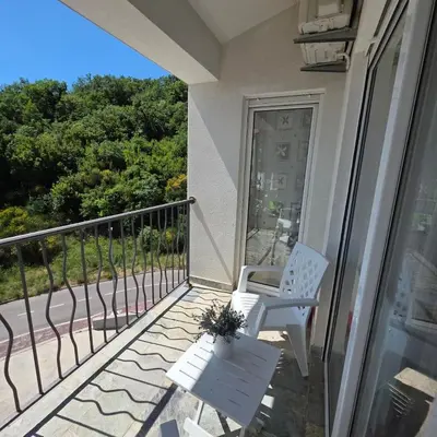 a balcony with a white chair and a table at Summer vacation near Sveti Stefan in Podličak