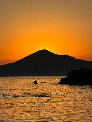 a sunset over a mountain with a boat in the water at Summer vacation near Sveti Stefan in Podličak