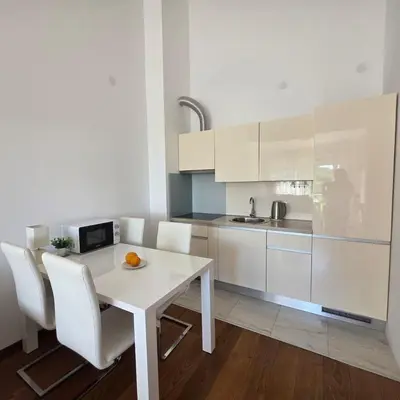 a white kitchen with a white table and chairs at Summer vacation near Sveti Stefan in Podličak