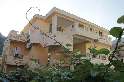 a yellow building with balconies and trees at Lilian Apartments in Budva