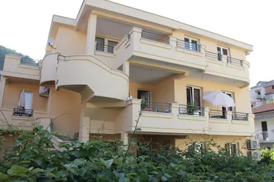 a yellow building with a balcony and an umbrella at Lilian Apartments in Budva