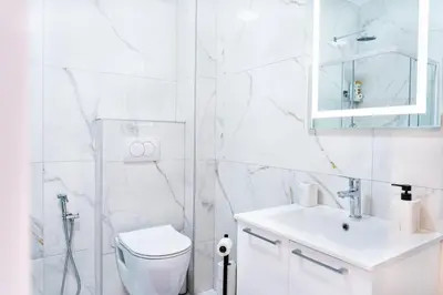 a white bathroom with a toilet and a sink at Apartment BAR M3B in Bar