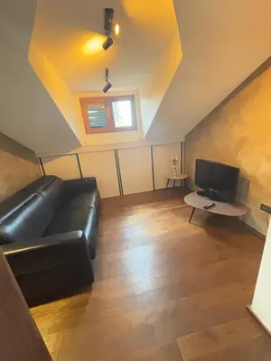 a living room with a black leather couch and a tv at Loft Suite in Budva