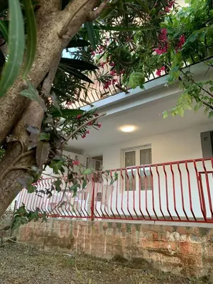 a red fence in front of a building with a tree at Utjeha house Ana in Utjeha