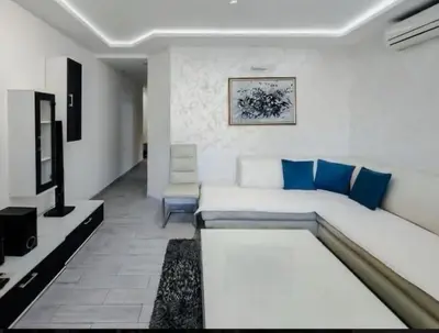 a living room with a white couch and blue pillows at Holiday 1 in Dobrota