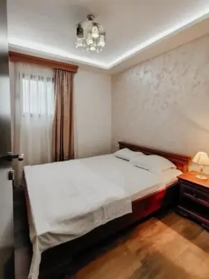 a bedroom with a large bed and a chandelier at Holiday 1 in Dobrota