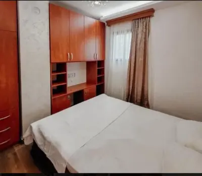 a bedroom with a white bed and wooden cabinets at Holiday 1 in Dobrota
