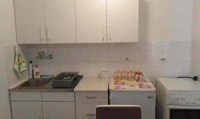 a kitchen with white cabinets and a sink and a stove at Apartment Boksi in Ulcinj