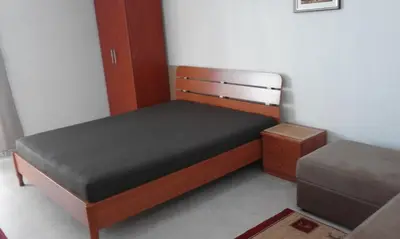 a small bedroom with a bed and a stool at Apartment Boksi in Ulcinj