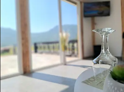 a wine glass sitting on a table with a view of the beach at Kutak prirode in Njeguši