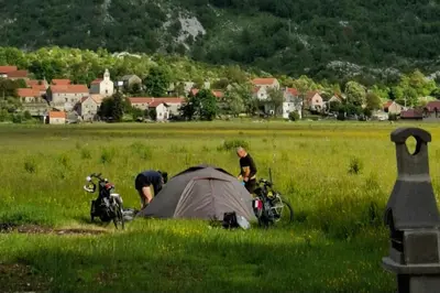 two people standing around a tent in a field at Kutak prirode in Njeguši