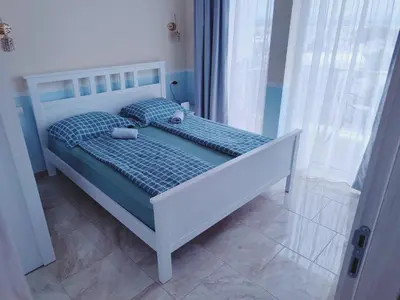a bedroom with a bed with a blue comforter at Apartman Zefir Ulcinj in Ulcinj