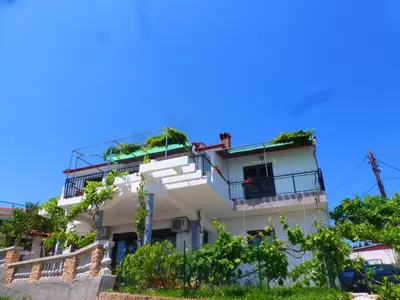 a white building with balconies and trees in front of a blue sky at Apartment Djakonovic Mladen in Ulcinj