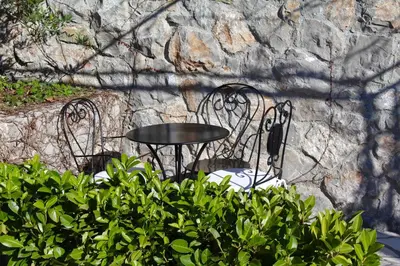 a black table and chairs in front of a stone wall at Hotel Opera Jaz in Budva