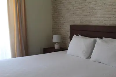 a bedroom with a bed with white pillows and a brick wall at Hotel Opera Jaz in Budva