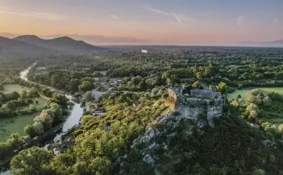 an old castle on a hill next to a river at Apartman Žabljak Crnojevića in Žabljak