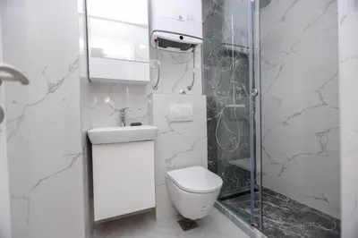 a white bathroom with a toilet and a shower at B1 first line apartments in Bar, Susanj