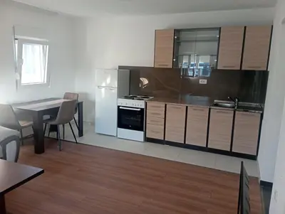 a kitchen with wooden cabinets and a table with a dining room at Niagara apartman in Podgorica
