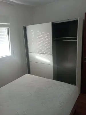 a white room with a bed and a refrigerator at Niagara apartman in Podgorica