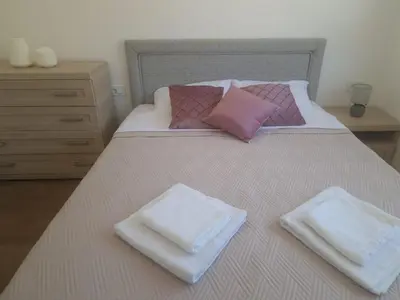 a bed with two white and pink pillows on it at Big Family apartment - 3BR in Budva