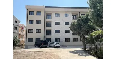 a large building with two cars parked in a parking lot at Big Family apartment - 3BR in Budva