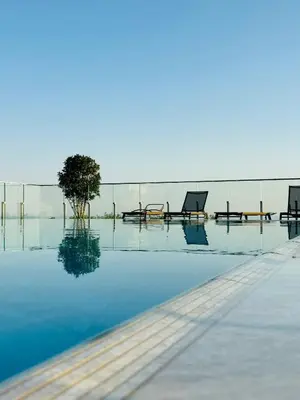 a pool with chairs and a tree in the water at Vuelo Sobre Bečići in Becici