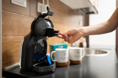 a person is reaching for a coffee maker on a counter at BlueMont Apartment in Podgorica