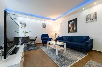 a living room with a blue couch and a tv at BlueMont Apartment in Podgorica