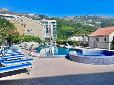 a pool with blue lounge chairs in a resort at Sunset studio Bečići in Becici