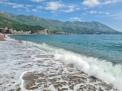 a wave breaking on a beach with mountains in the background at Sunset studio Bečići in Becici