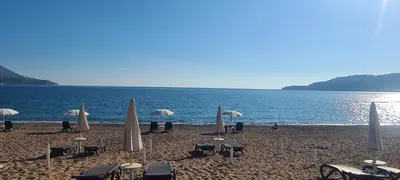 a beach with umbrellas and tables and chairs and the ocean at Sunset studio Bečići in Becici