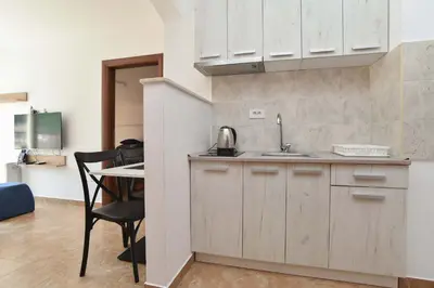 a kitchen with white cabinets and a table and a chair at Omega 1 Apartment Budva in Budva