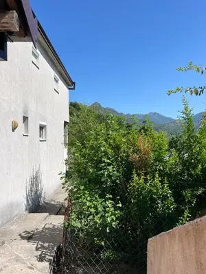 a fence next to a building with mountains in the background at APARTMENTS Mir in Virpazar