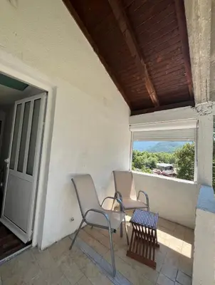 two chairs and a table on a porch with a window at APARTMENTS Mir in Virpazar